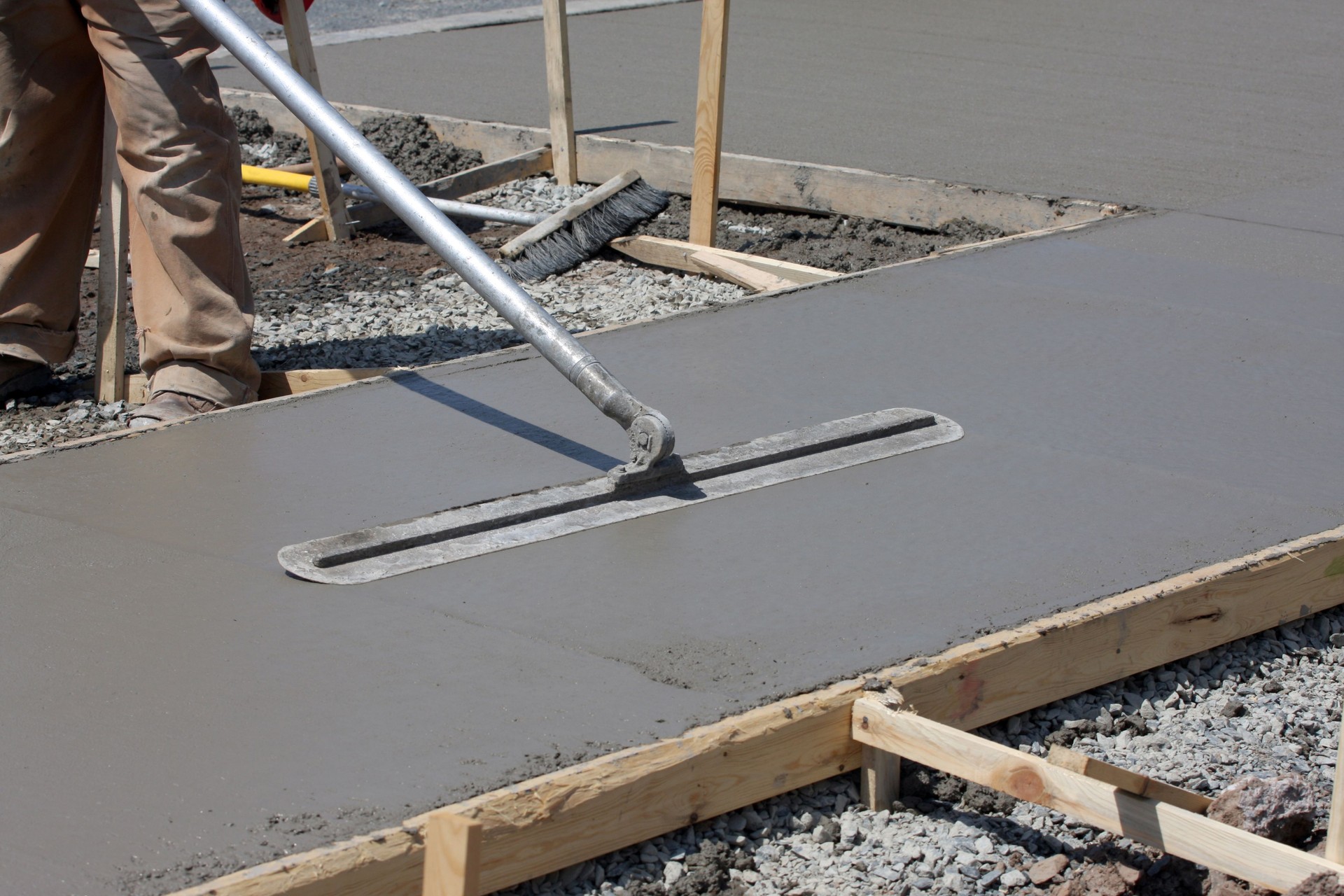 Construction worker smoothing out concrete on work site